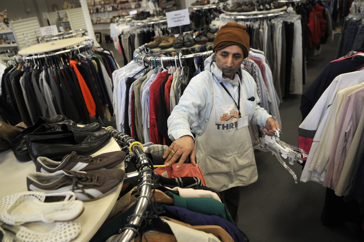 Global Neighborhood thrift store employee Hari Adhikari, from Bhutan, makes the clothes rack presentable. (Dan Pelle)