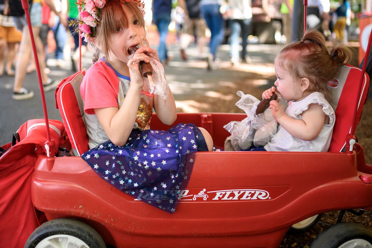 Aurelia Blue, 5, and her sister Nova, 2, enjoy bananas dipped in chocolate during the 2019 Pig Out in the Park in Riverfront Park. The event is back after missing two years, thanks to the COVID-19 pandemic.  (COLIN MULVANY)