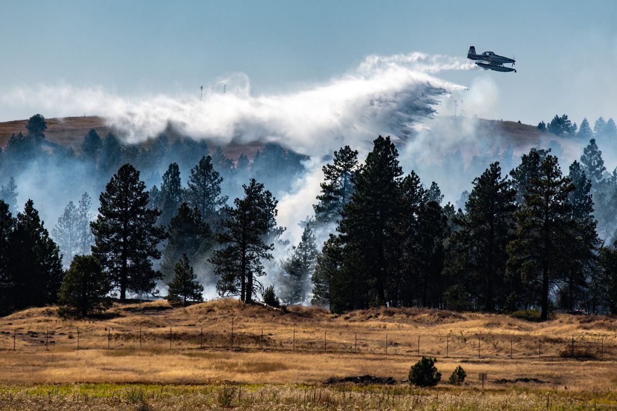 An aircraft makes a fire water drop Thursday on a fast-moving brush fire. On Saturday, the first was almost completely contained.  (Colin Mulvany/THE SPOKESMAN-REVIEW)