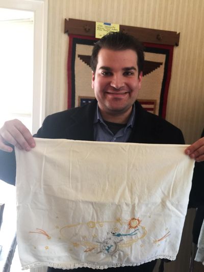 This undated photo provided by Adam Sackowitz, of Queens, New York, shows him displaying an embroidered pillowcase with celestial bodies on it that belonged to the late John Glenn. (Associated Press)