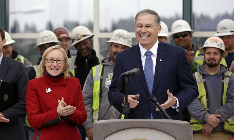 Washington Gov. Jay Inslee with former Transportation Secretary Lynn Peterson, left, and construction workers behind speaks from the construction site of a new floating bridge on Lake Washington in Medina, Wash., in 2014. The state Senate has rejected the gubernatorial appointment of Peterson, ousting her from the job she has held since shortly after Inslee took office in 2012. The rare move was taken by the Senate Friday, Feb. 5, 2016, with majority Republicans and a Democrat who caucuses with them voting 25-21 to remove Peterson.  (AP Photo/Elaine Thompson)