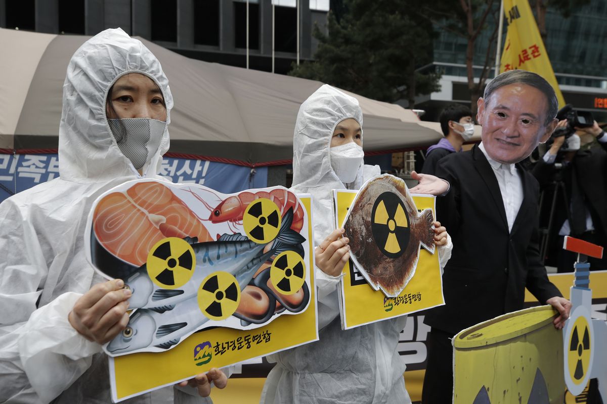 FILE - In this April 13, 2021, file photo, environmental activists wearing a mask of Japanese Prime Minister Yoshihide Suga and protective suits perform to denounce the Japanese government