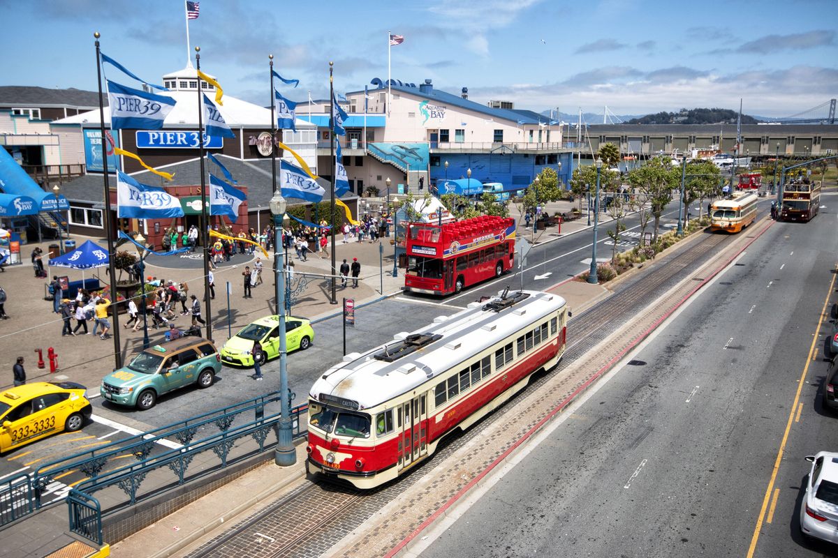 A historic streetcar painted in honor of Dallas, Texas, passes Pier 39, a popular tourist destination, in June 2016. Streetcars fell out of favor in most of the country after the automobile boom of the 1950s, but the city by the bay still uses them. (Justin Franz / For the Washington Post)
