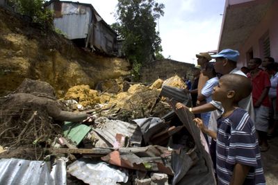 Residents stand in front of several houses destroyed by a landslide in Guachupita, Santo Domingo, on Wednesday. Authorities said that eight people died, including two infants, in the landslide triggered by Hurricane Gustav.  (Associated Press / The Spokesman-Review)