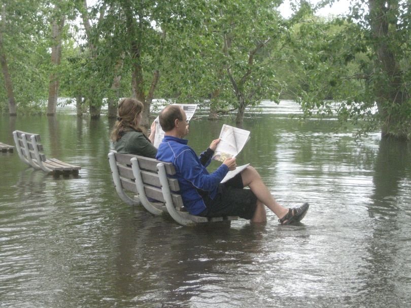 Ramsey Larson and her father, Kent, read The Spokesman-Review from a bench along the Spokane River and Centennial Trail near Avista on June 12, 2011.  The river was still running high with runoff. (Courtesy photo)