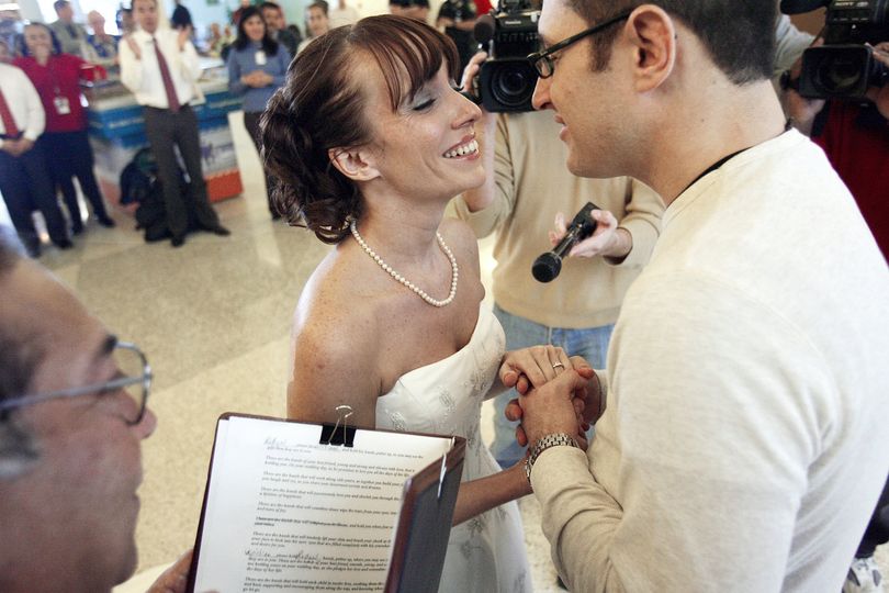 Robyn Moore with her fiancee, William Acosta, right, exchange vows at the Corpus Christi, Texas International Airport on Monday, Dec. 21, 2009 after his arrival from Toledo, Ohio. Robyn Moore was at the airport waiting for him in her wedding dress with Justice of the Peace, Robert 