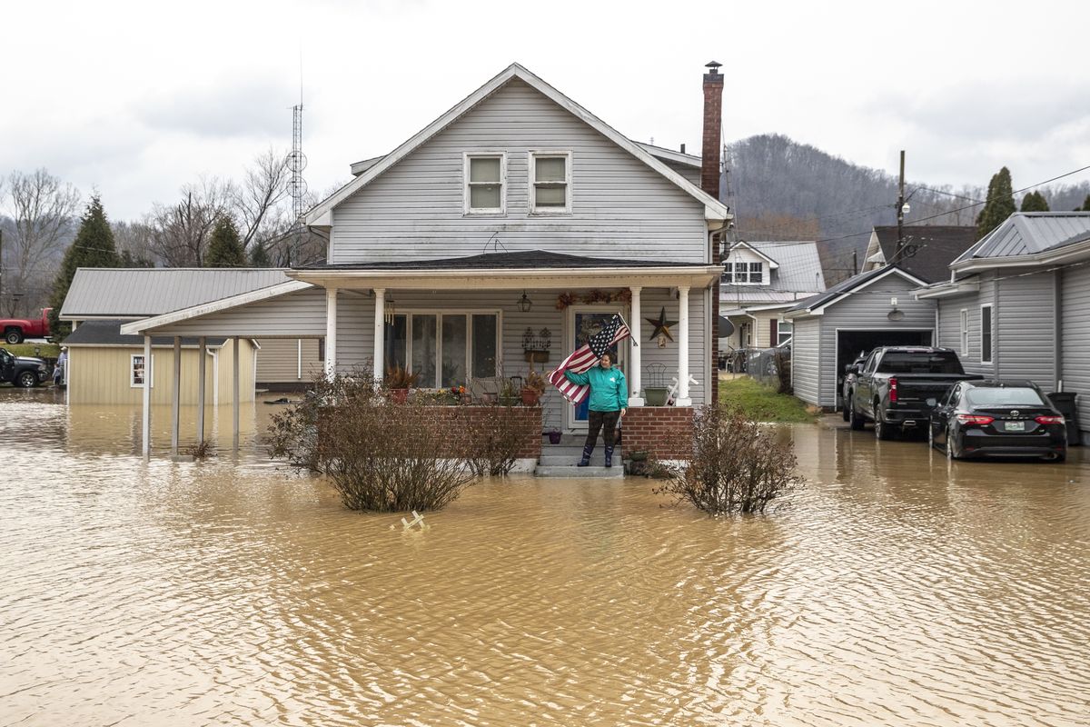 Catherine Castle stands on the porch of her home Monday in Paintsville, Ky., as floodwaters approach.  (Ryan C. Hermens)