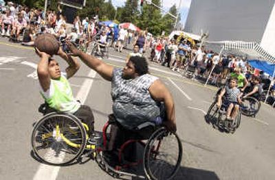 
Jose Adriano of the Mean Green Machine puts up a shot over the outstretched arm of Burnt Rubber's Malcom Tatum during their Hoopfest game Sunday.  Both teams play for the Jr. Sonics Wheelchair team in Seattle, and the athletes range from 7 to 18 years old. 
 (Photos by J. Bart Rayniak / The Spokesman-Review)