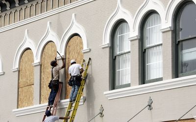 Workers cover windows with plywood in downtown Gulfport, Miss.,  on Sunday.  (Associated Press / The Spokesman-Review)