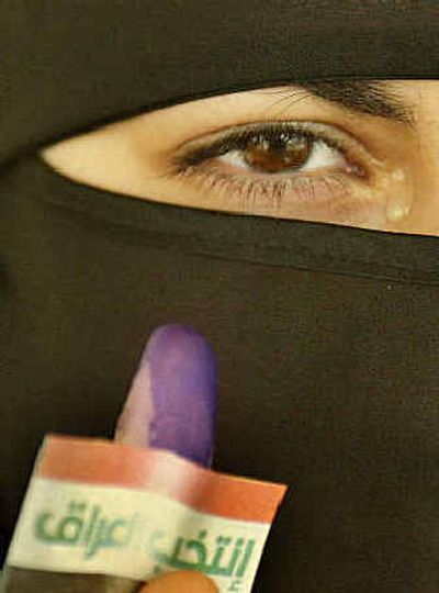 
With tears rolling down her eyes, an Iraqi woman shows off her finger stained with ink and a small card reading 