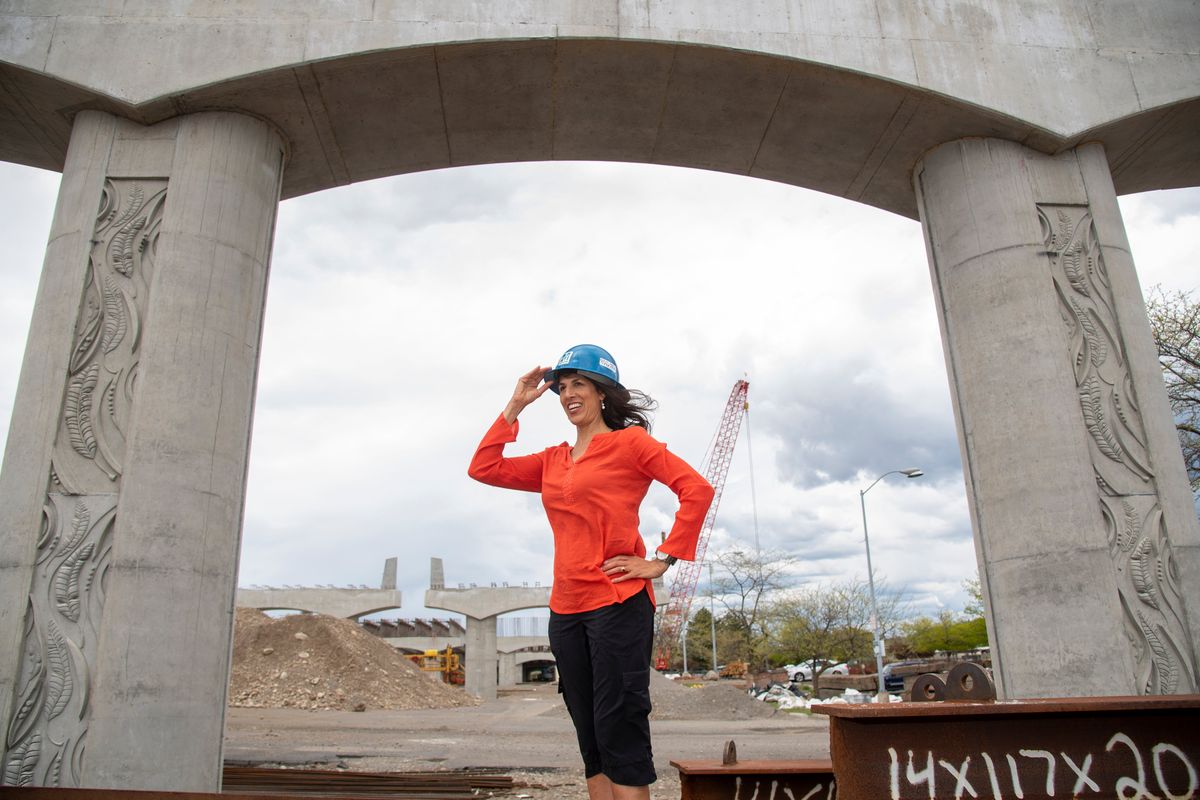 Artist Melissa Cole stands near one of the massive supports for the elevated North-South Corridor in the parking lot of Spokane Community College on Monday.  (Jesse Tinsley/The Spokesman-Review)
