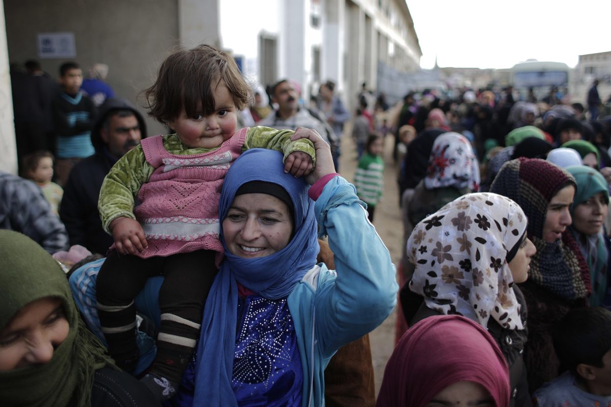 Syrian women who were displaced with their family from eastern Aleppo wait in line to receive aid in  Jibreen  on Saturday, Dec. 3, 2016. (Hassan Ammar / Associated Press)