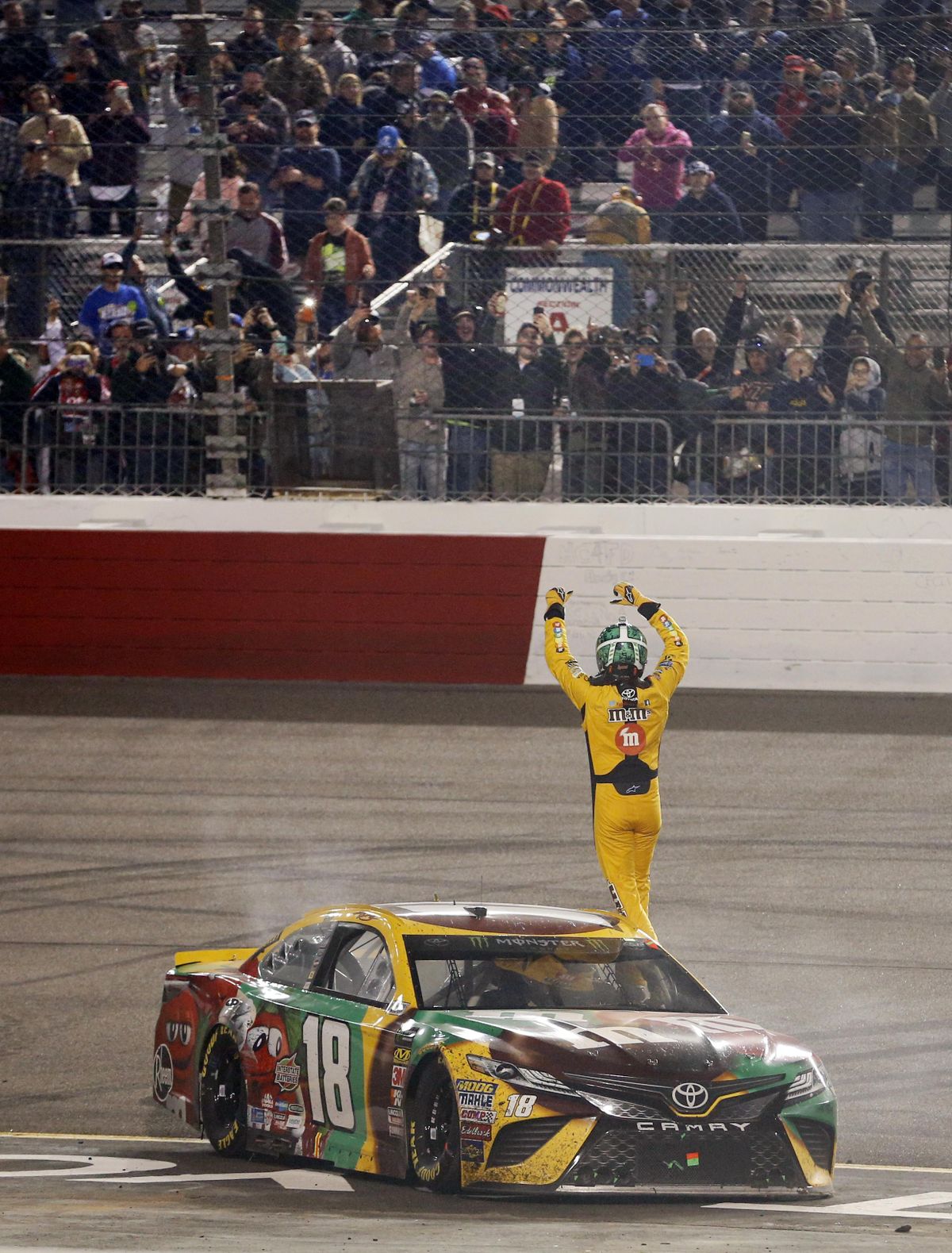 Kyle Busch waves to the fans as he celebrates after winning the NASCAR Cup Series auto race at Richmond Raceway in Richmond, Va., Saturday, April 21, 2018. (Steve Helber / Associated Press)