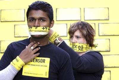 One demonstrator ties a gag on another while calling for free speech and greater access to the Internet in China during a protest this week in Sydney, Australia.  (Associated Press / The Spokesman-Review)