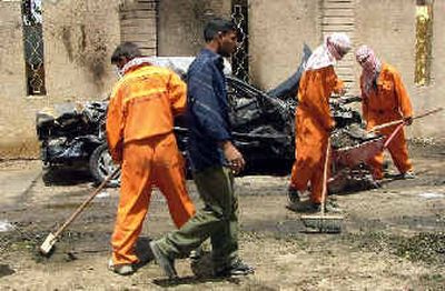 
Workers sweep away the debris after suicide bombers blew themselves up, killing at least 25 people and wounding 100 in Hillah, Iraq, on Monday. The bombers attacked a government building where Iraqi police were protesting.
 (Associated Press / The Spokesman-Review)