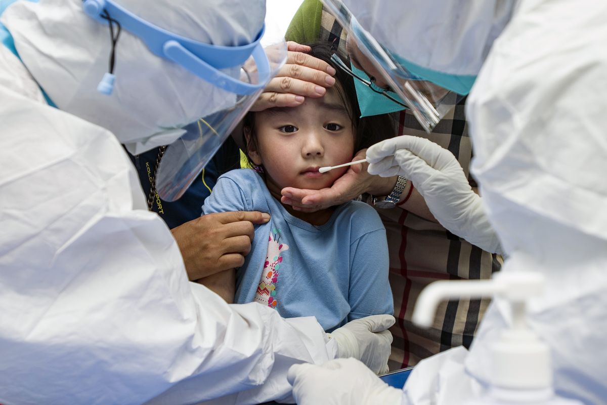 A child reacts to a throat swab during mass testing for COVID-19 in Wuhan, China, on Tuesday.  (STR)