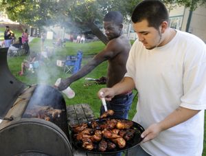 Brutis Tensley, left,  and Dan Aragon tend to chicken on the barbecue  as they participate in the National Night Out on Tuesday at the Richard Allen Apartments in Spokane.  (Photos by Dan Pelle / The Spokesman-Review)