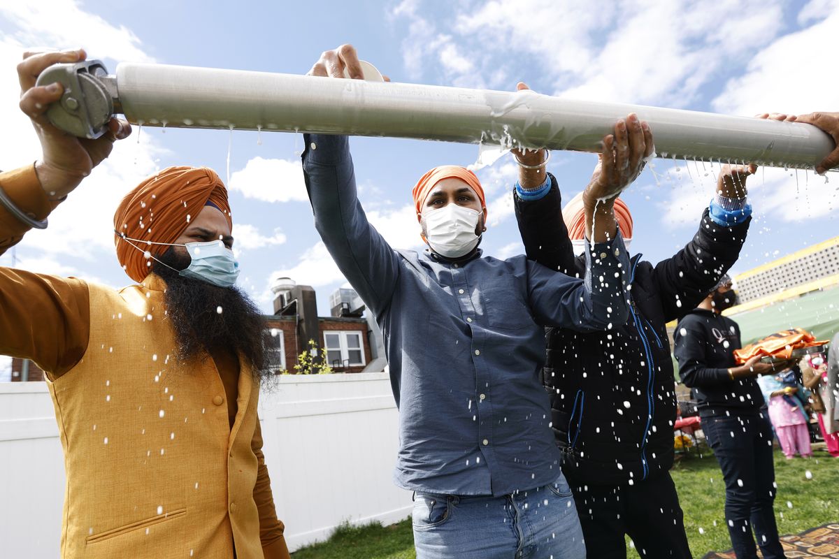Jasbir Singh, left, and Vijay Singh wash a flagpole with milk Tuesday as part of a ceremonial changing of the Sikh flag during Vaisakhi celebrations at Guru Nanak Darbar of Long Island in Hicksville, N.Y.  (Jason DeCrow)