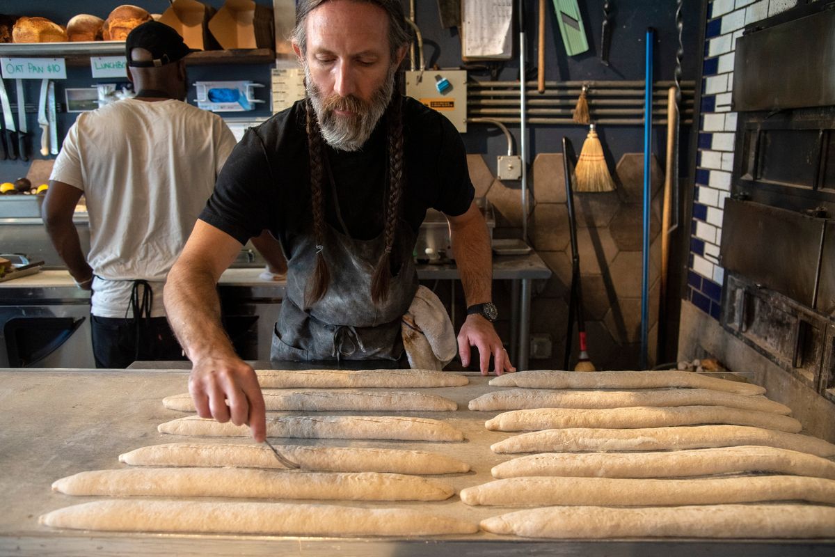 Shaun Thompson Duffy, co-founder of The Grain Shed, a bakery and restaurant at 1026 E. Newark Avenue in the Perry District, makes slits in the tops of baguettes last week before baking them at the restaurant.  (Jesse Tinsley/The Spokesman-Review)