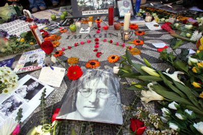 
A photo of John Lennon along with flowers, candles, and other memorabilia are placed on the 