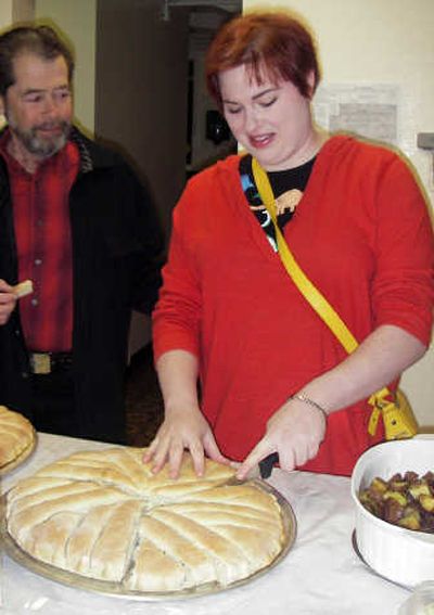 
Sophronia Supica slices pieces of hambasha during Holy Trinity Greek Orthodox Church's Lenten potluck last week. The hambasha – a traditional bread from Eritrea – was baked by her mother, Presvytera Irene Supica. Athanasios Schumacher, the church's subdeacon, enjoys a slice.Correspondent
 (Virginia de Leon Correspondent / The Spokesman-Review)