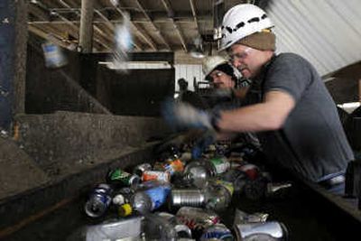 
Bottles fly as Robert Searcy, right, and Steve Smith work furiously to remove plastic bottles from the passing conveyor belt carrying PAT– short for plastic, aluminum and tin – Friday at Spokane Recycling Products. 
 (Jesse Tinsley / The Spokesman-Review)