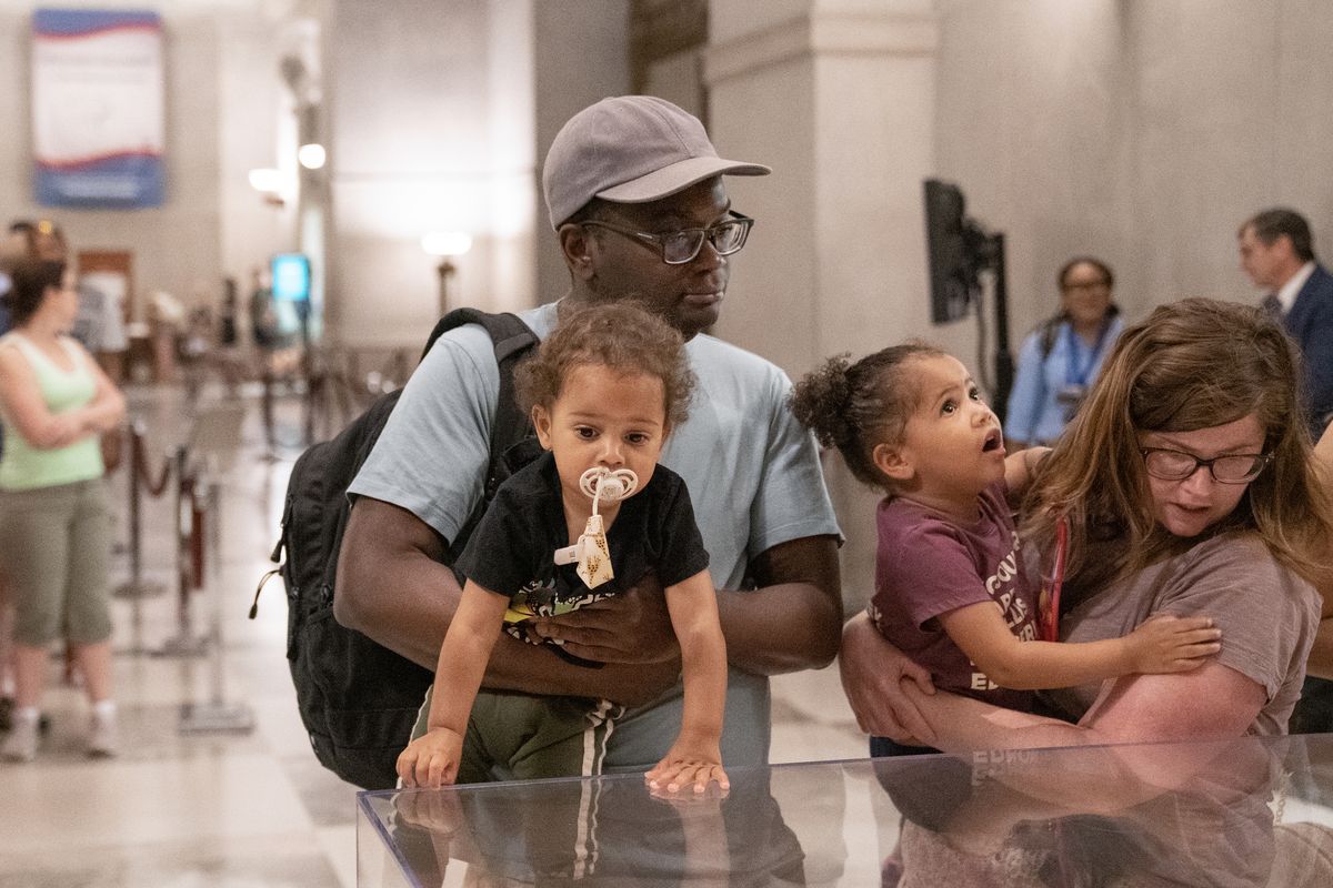 Jonathan Massaquoi, left, holds one-year-old Miles while Colleen Massaquoi, far right, holds three-year-old Zora as they view the Emancipation Proclamation at the National Archives in Washington on Saturday. (Minh Connors/The Washington Post)