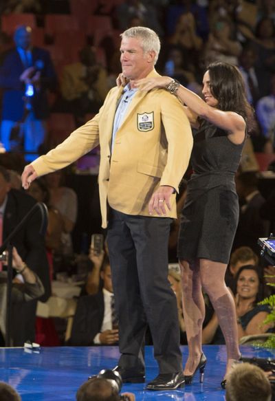 Brett Favre receives his gold jacket from his wife, Deanna, at the Pro Football Hall of Fame  dinner on Thursday. (BOB ROSSITER / Associated Press)