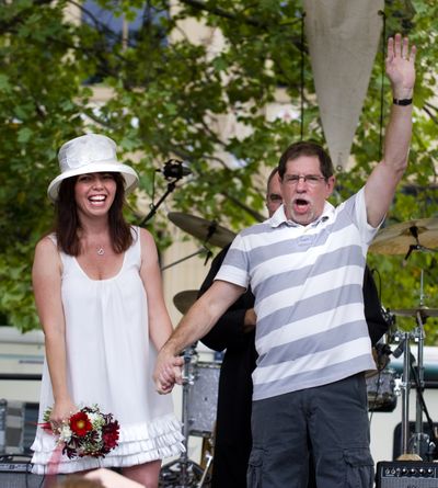 After saying their wedding vows, Jack Gibson and Kimberly Knox  turn to greet the crowd of family, friends and onlookers gathered at the main stage at Pig Out in the Park on Saturday in Riverfront Park. (Colin Mulvany / The Spokesman-Review)