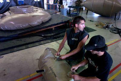 
Ryan Combs, tank cell lead employee at Berg Cos., works with Pat Carias to roll a 1,000-gallon polyurethane tank. The company has a five-year contract worth $17.5 million to make 3,000-gallon tanks, shown at left in the background, for the Army.
 (Jed Conklin / The Spokesman-Review)