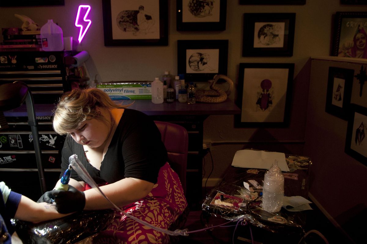 Tattoo artist and co-owner Christina Villagomez of the Electric Age Tattoo in Coeur d’Alene works on a tattoo during a charity drive for the Children’s Village on Friday. (Kathy Plonka / The Spokesman-Review)