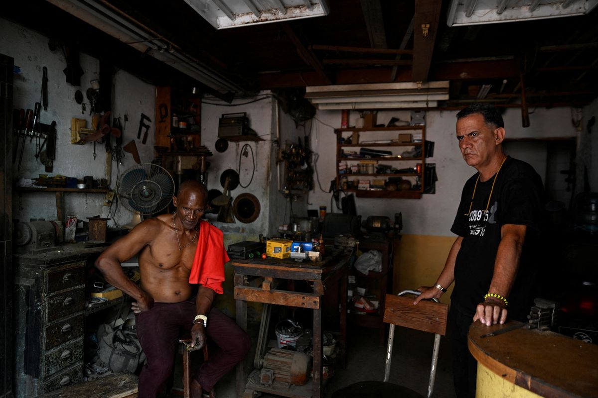 Manuel and a fellow locksmith sit in their shop during a blackout as Cuba