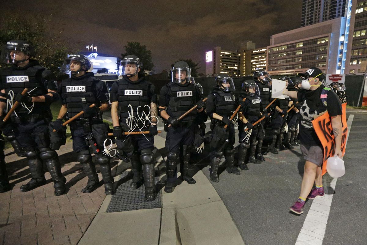 A protester walks in front of a line of police officers blocking the access road to I-277 on the third night of protests in Charlotte, N.C. Thursday, Sept. 22, 2016, following Tuesday’s fatal police shooting of Keith Lamont Scott. (Chuck Burton / Associated Press)
