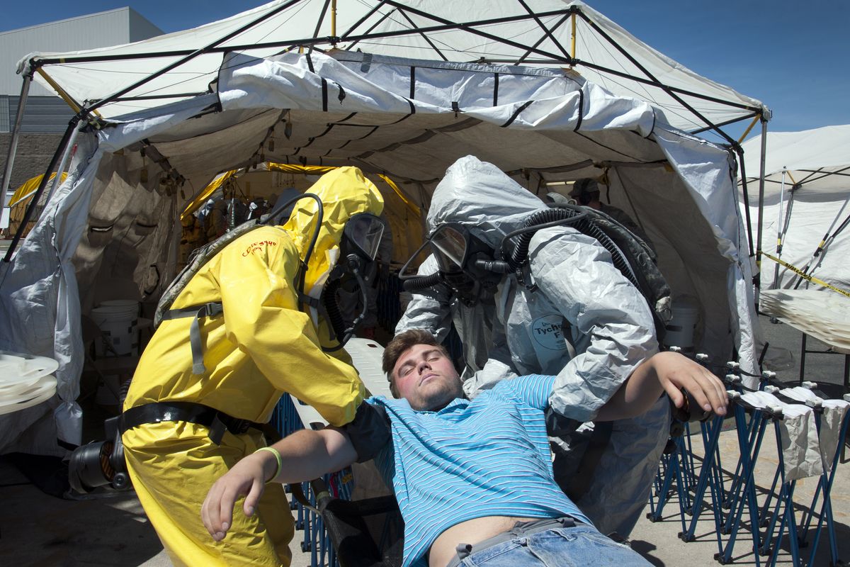 Washington State National Guard forces in decontamination suits attend to “victim” Sergey Grankin during training June 11 in Spokane. (Dan Pelle)