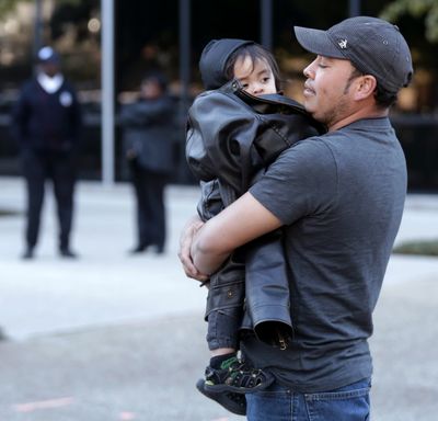 Denis Cherino, of Honduras, holds his son, Denis, as activists protest at the U.S. Citizenship and Immigration Services office in New Orleans on Wednesday. (Associated Press)