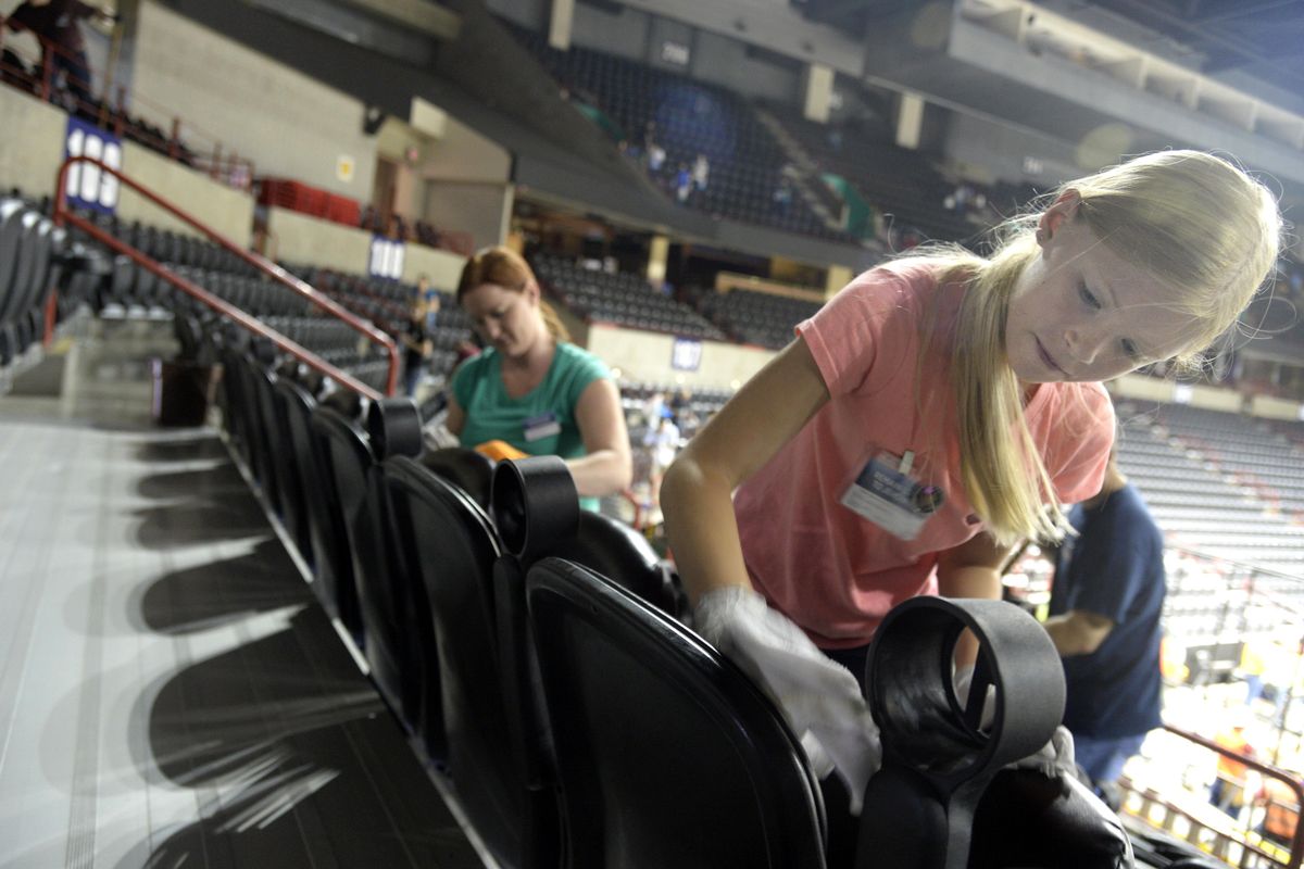 Volunteer Ellie Labrucherie, 8, and her mother Amanda, left, wipe down seats in the Spokane Arena, Thursday, June 30, 2016. V (Jesse Tinsley / The Spokesman-Review)