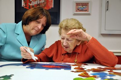 Barbara Drum helps her mother work a puzzle in the community/activity room. (Diedra Laird / The Spokesman-Review)
