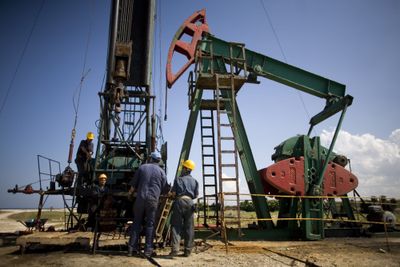 Workers stand next to an oil well pump in Brisas Del Mar, Cuba. It has been four years since the U.S. Geological Survey first estimated that Cuban waters could contain nearly 10 billion barrels of undersea oil. Foreign energy firms have signed up to help hunt for offshore oil north of the island, but only 21 of 59 Cuban deep-sea blocks have been purchased since they were put up for auction in 1999.  (Associated Press / The Spokesman-Review)