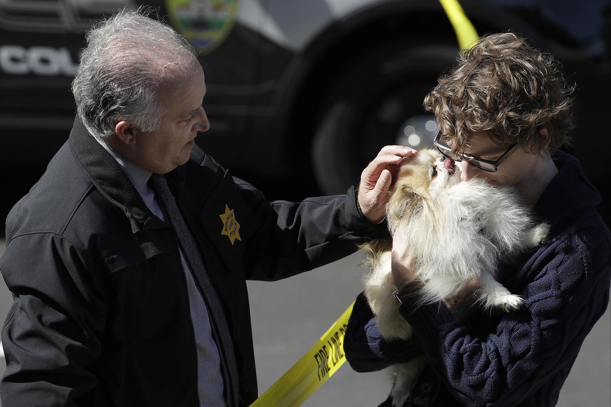 Burlingame Chief of Police Eric Wollman, left, hands a dog named Kimba to a man who wished to remain unidentified but said he worked for YouTube, outside the company