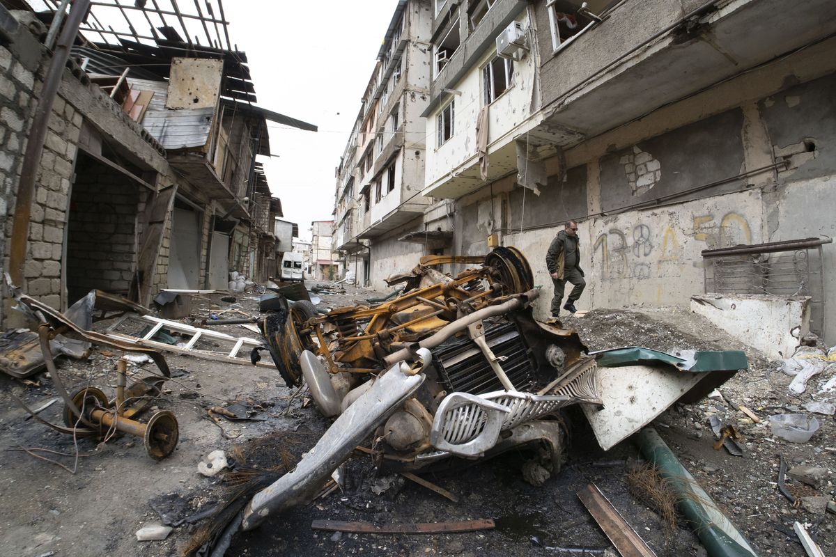 A man walks in the yard of an apartment building damaged by shelling by Azerbaijan