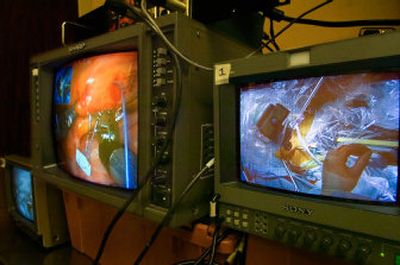 
Video monitors show the robotic heart procedure being performed by Drs. Leland Siwek and Branden Reynolds at Sacred Heart Medical Center on Friday. The screen at right looks down on the patient's chest, showing the ports for instruments and cameras while the one at left shows the instruments working on the heart. The two surgeons are pioneering the use of robotic equipment to minimize the invasive impacts of more traditional large opening procedures. 
 (The Spokesman-Review)