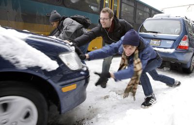 Pedestrians stop to help a motorist stuck on ice Tuesday following a weekend snowstorm  in Seattle.  (Associated Press / The Spokesman-Review)