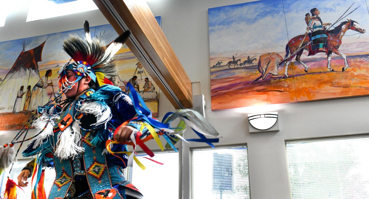 Dakota Madera against a backdrop of paintings depicting Native American scenes during The Native Project’s 30th anniversary block party on Friday in Spokane. (Tyler Tjomsland / The Spokesman-Review)