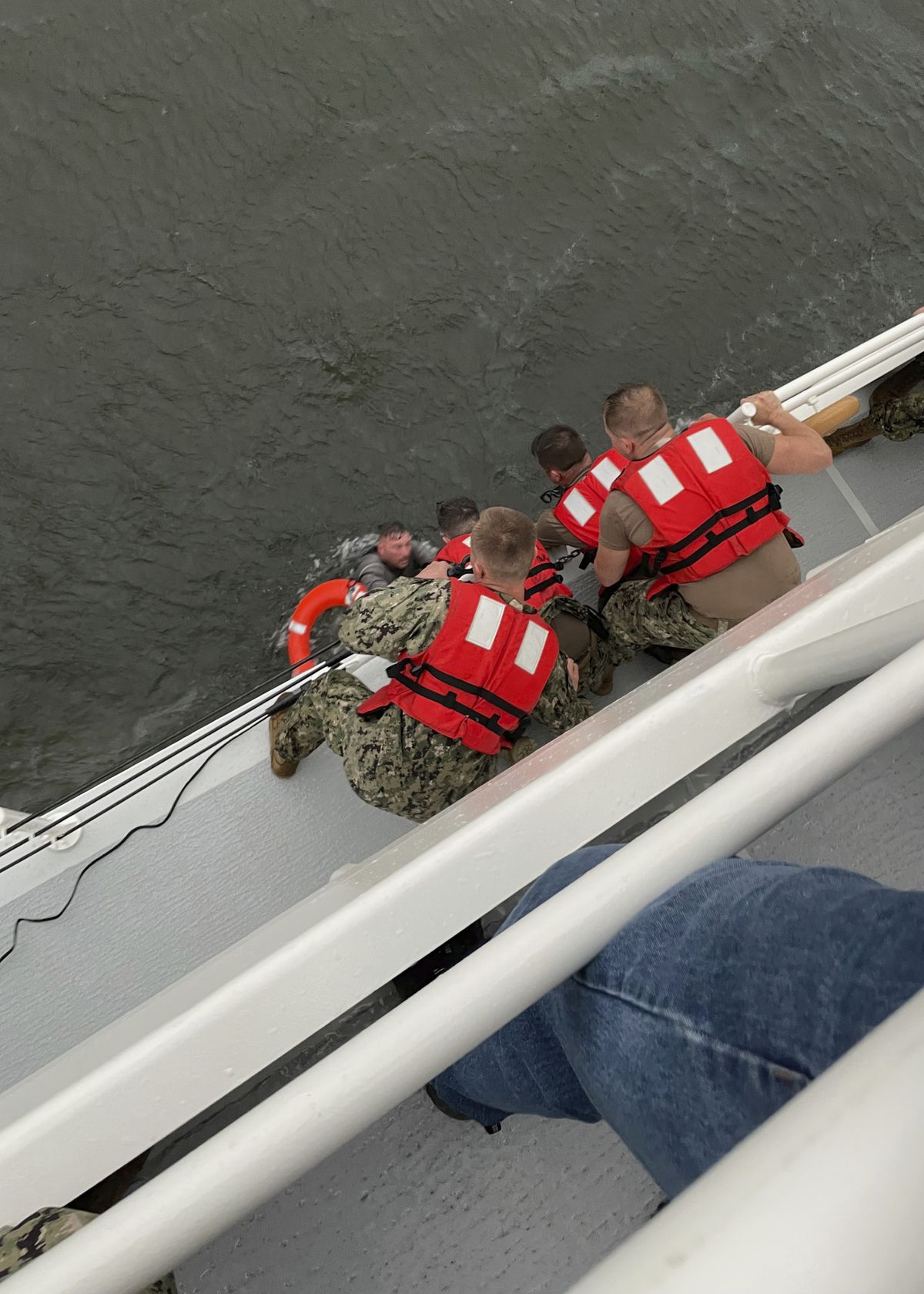 The crew of the Coast Guard Cutter Glenn Harris pulls a person from the water Tuesday, April 13, 2021 after a 175-foot commercial lift boat capsized 8 miles south of Grand Isle, Louisiana. The Coast Guard and multiple other boats rescued six people onboard a commercial lift boat that capsized off the coast of Louisiana on Tuesday night and were searching for more, the agency said.  (HOGP)