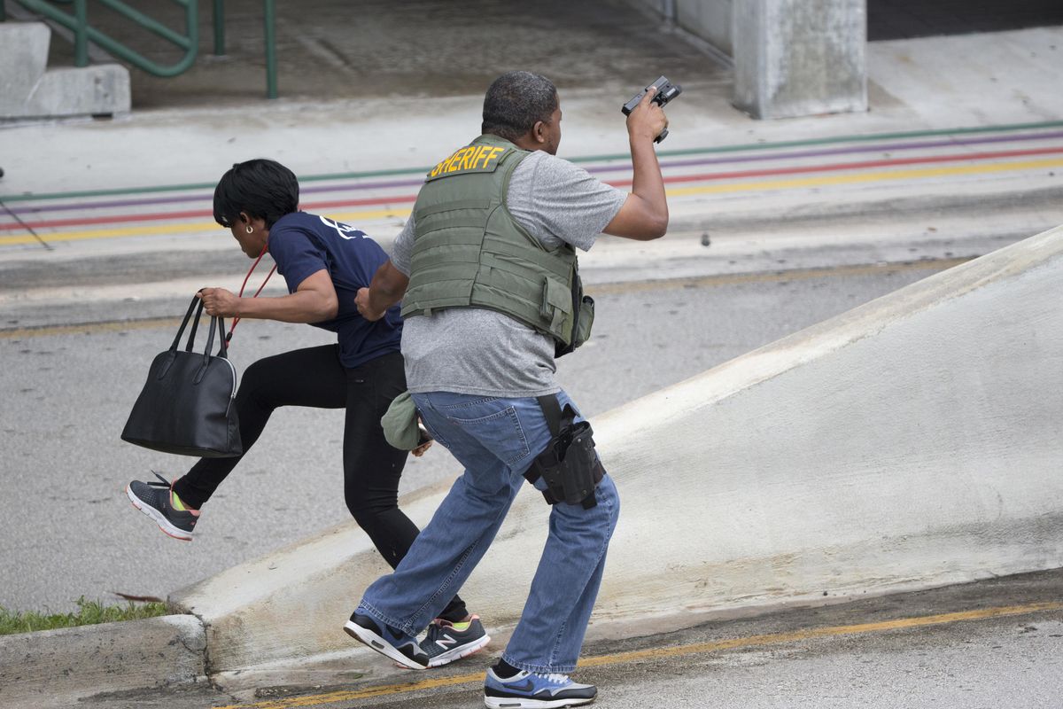 A law enforcement officer evacuates a civilian from an area at Fort LauderdaleHollywood International Airport, Friday, Jan. 6, 2017, in Fort Lauderdale, Fla. A gunman opened fire in the baggage claim area at the airport Friday, killing several people and wounding others before being taken into custody in an attack that sent panicked passengers running out of the terminal and onto the tarmac, authorities said. (Wilfredo Lee / Associated Press)