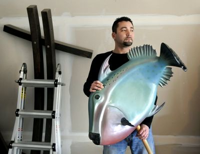 Michael Larsen has been an industrial sculptor for the past 13 years. He holds his triggerfish creation made from fiberglass and foam core.  (Dan Pelle)