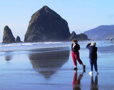 A visitor poses in front of Haystack Rock in Cannon Beach, Ore. (Chris Wille/SR file photo)