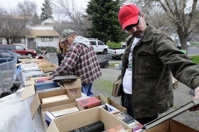 Joel Cummings, right, sorts through books at a garage sale on East Bridgeport Avenue on Friday. Mild spring weather brings shoppers out for bargains.  (Jesse Tinsley / The Spokesman-Review)