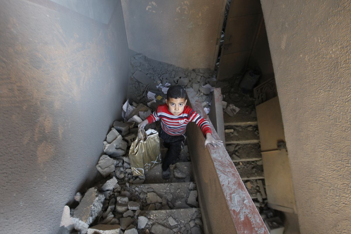 A Palestinian boy walks up the stairs of a house destroyed Sunday by an Israeli strike in Gaza City on Monday. The Palestinian civilian death toll mounted Monday as Israeli attacks continued. (Associated Press)