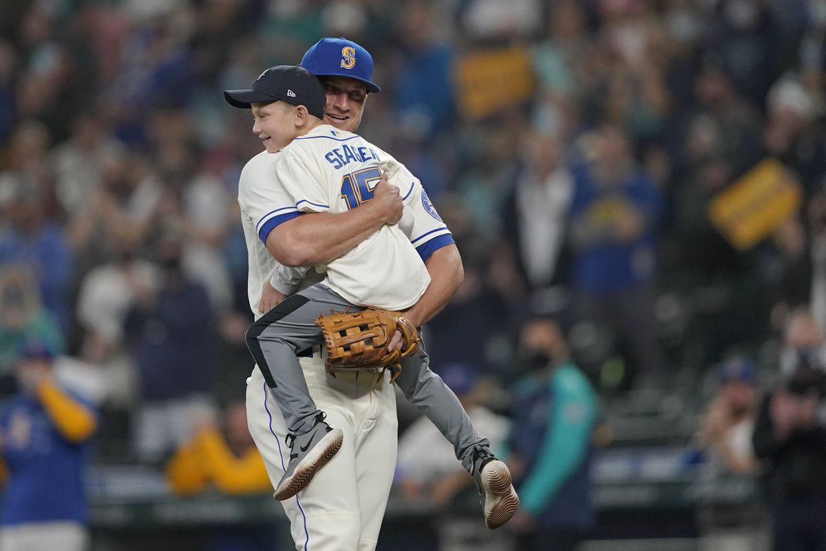 Seattle Mariners third baseman Kyle Seager hugs his son Crue, after Crue threw out the the first pitch of a baseball game against the Los Angeles Angels to his Dad, Sunday, Oct. 3, 2021, in Seattle.  (Associated Press)